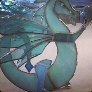 A stained glass dragon is sitting on a table.