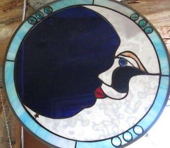 A stained glass painting of a woman 's face is hanging on a wall