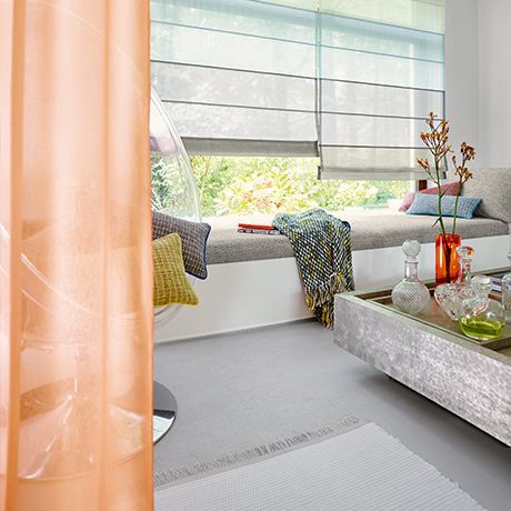 Blick in ein Zimmer mit Plissee und Vertikaljalousien