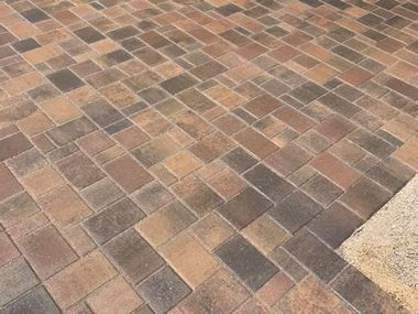 Multi-colored rectangular pavers in a herringbone pattern create a patio surface.