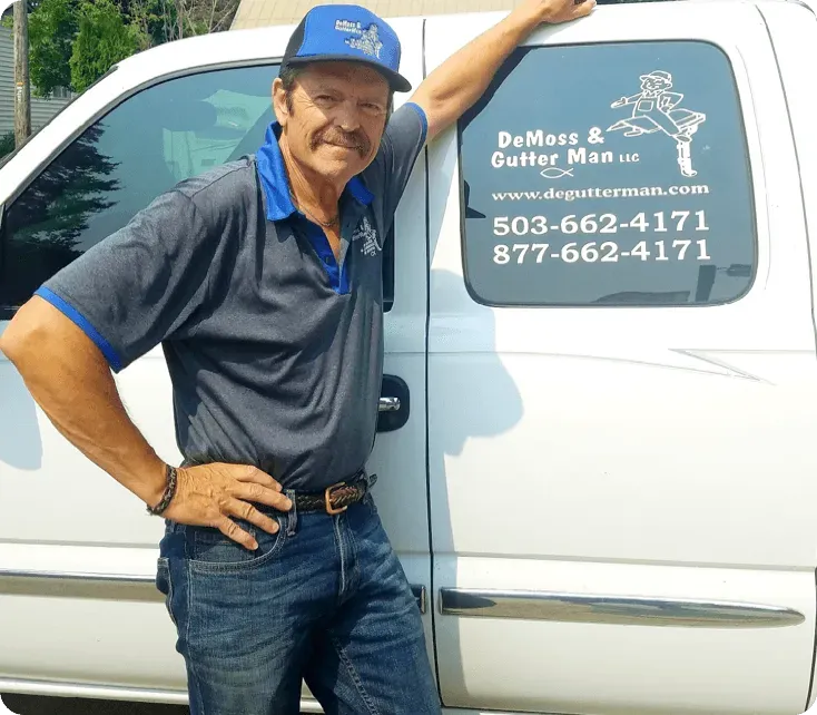 Man in blue shirt and cap leaning on white service van with company logo and phone numbers