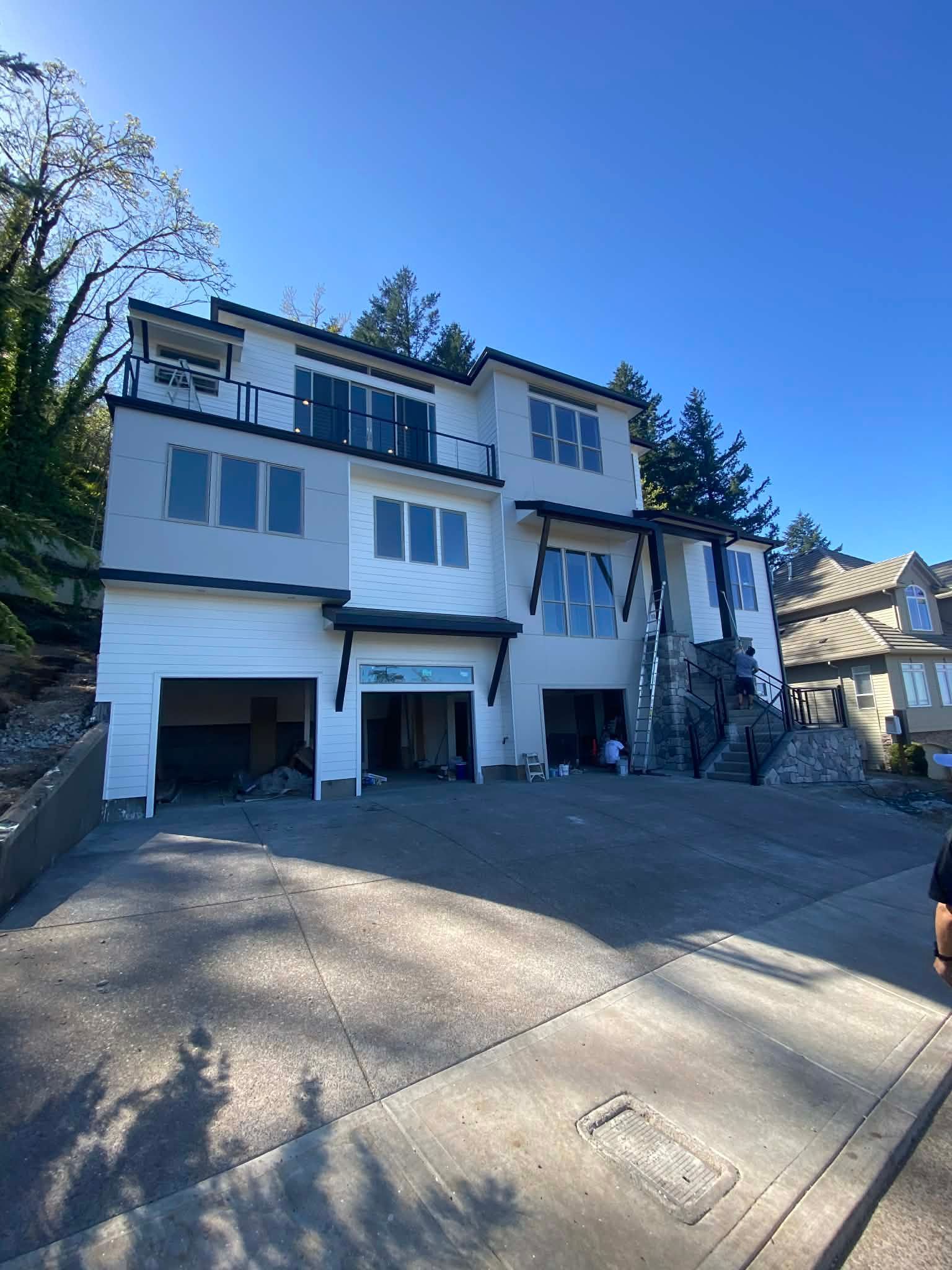White multi-story house with garage and driveway on a sunny day