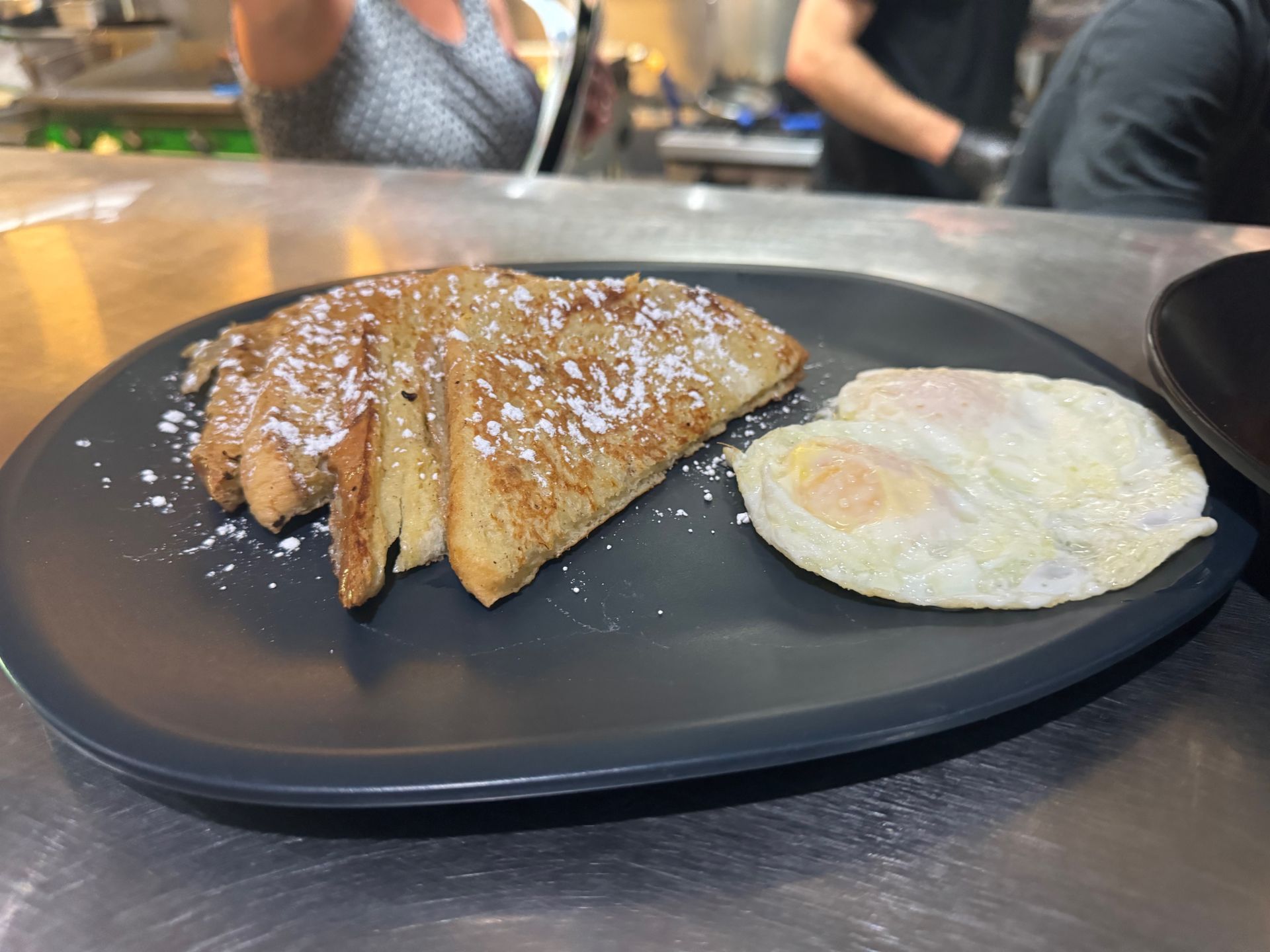 A black plate topped with french toast and eggs