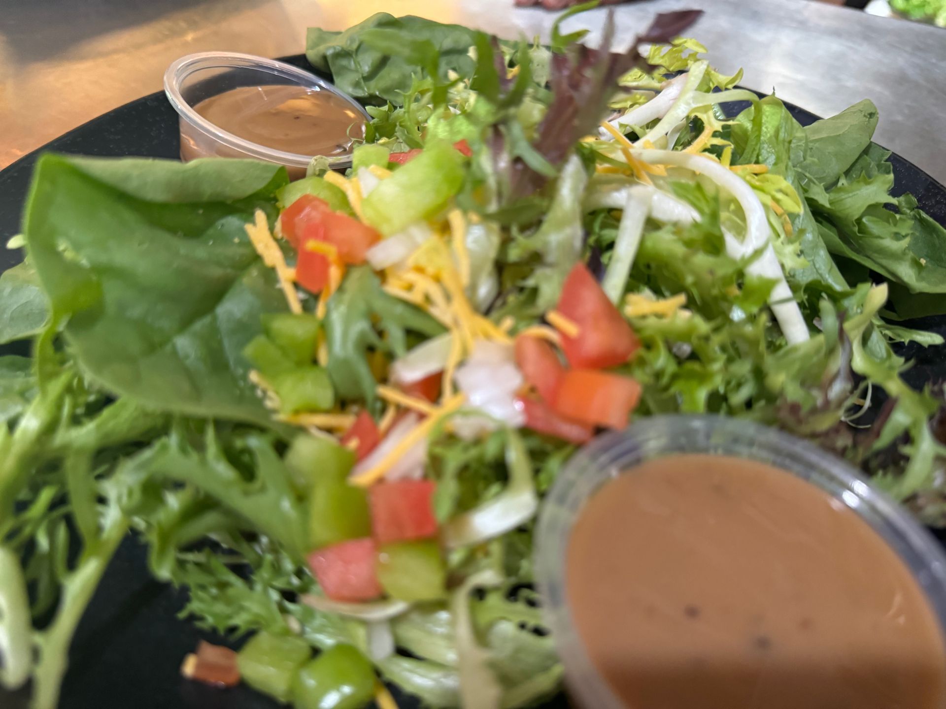 A close up of a salad on a plate with a dipping sauce.