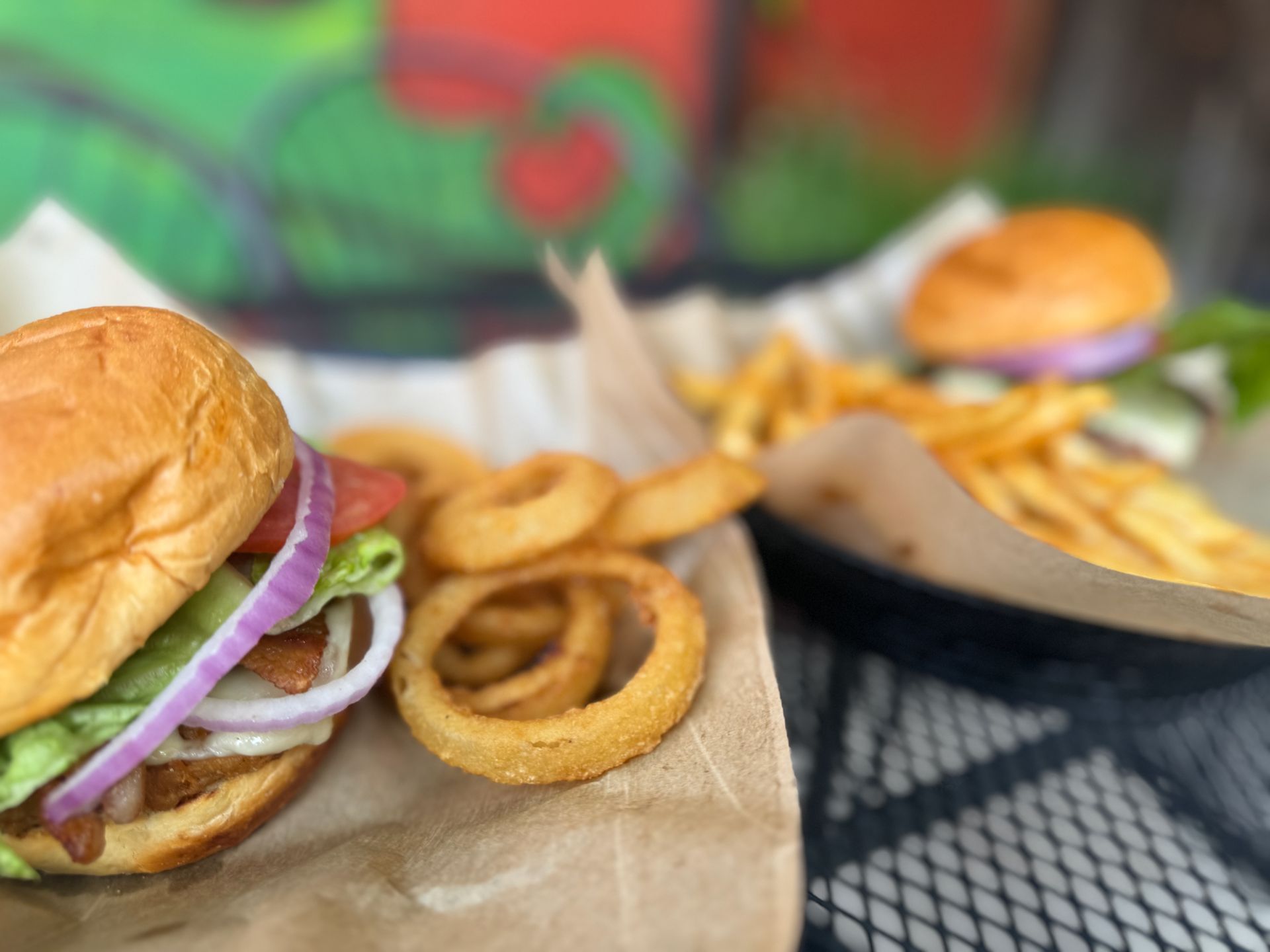 A close up of a hamburger and onion rings on a table.