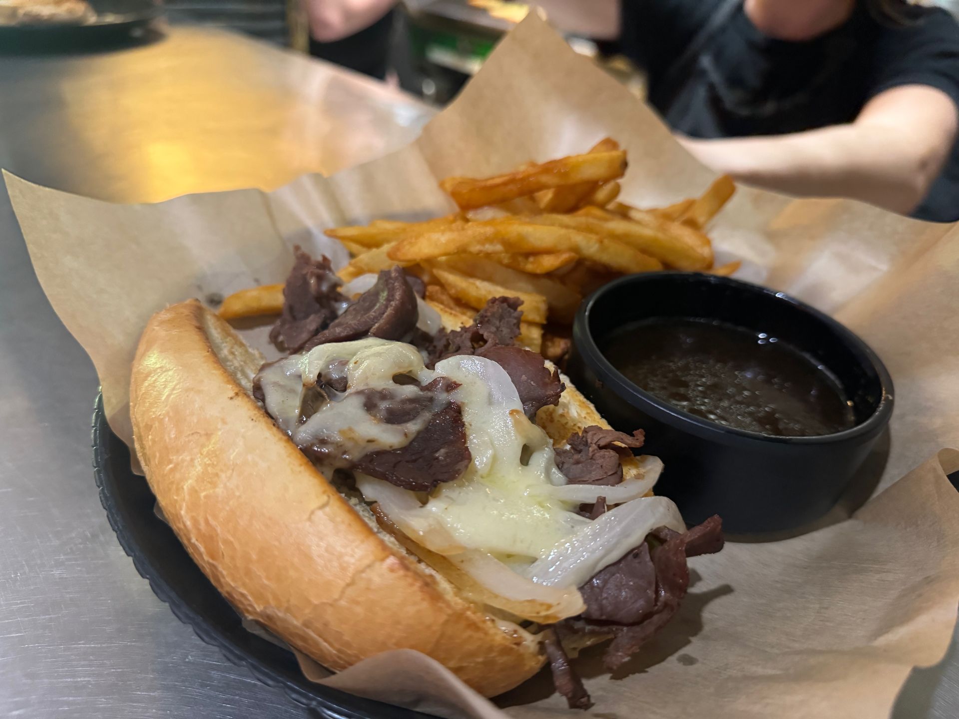 A steak sandwich with french fries and gravy on a plate.