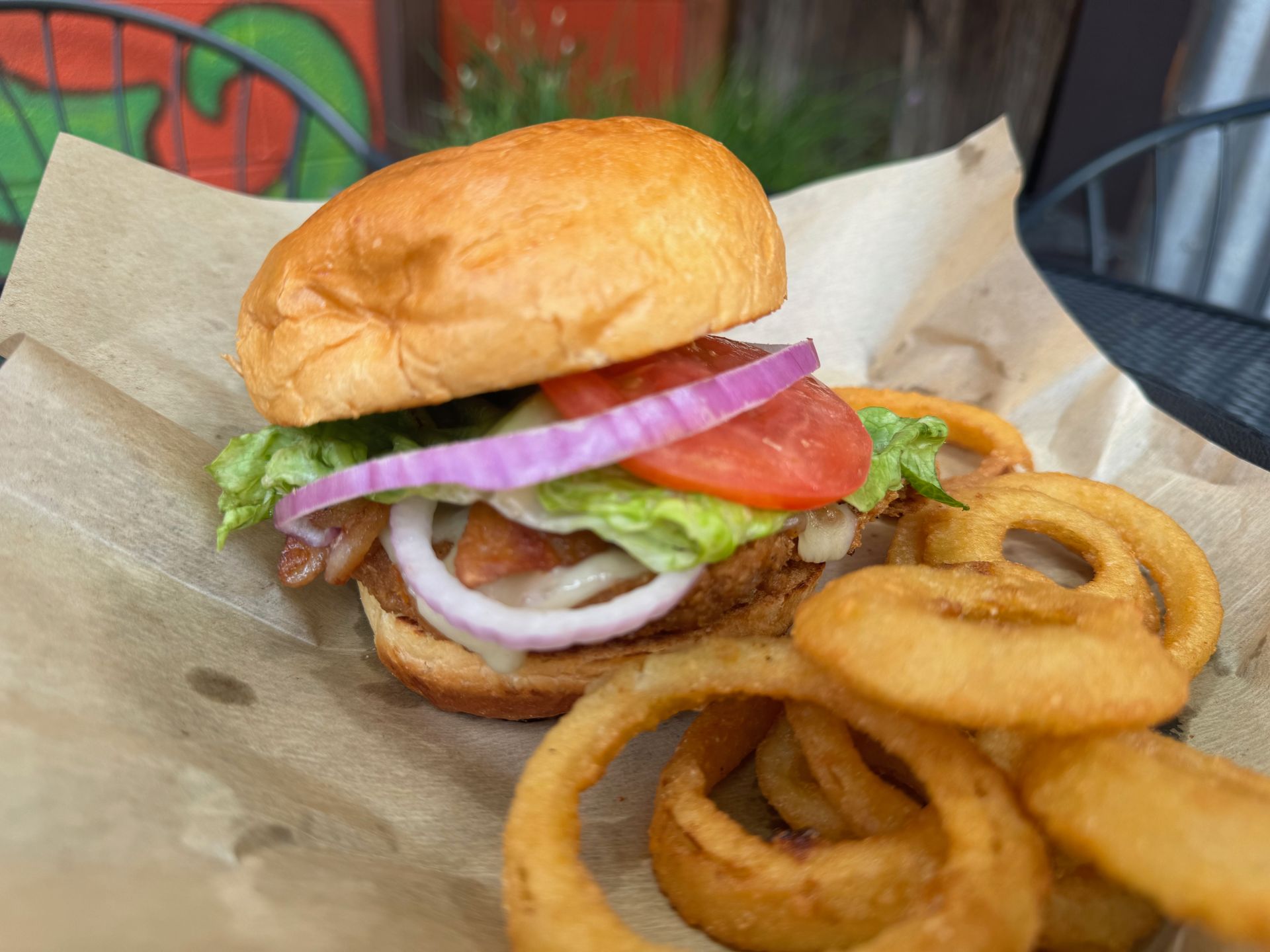 A close up of a hamburger and onion rings on a table.