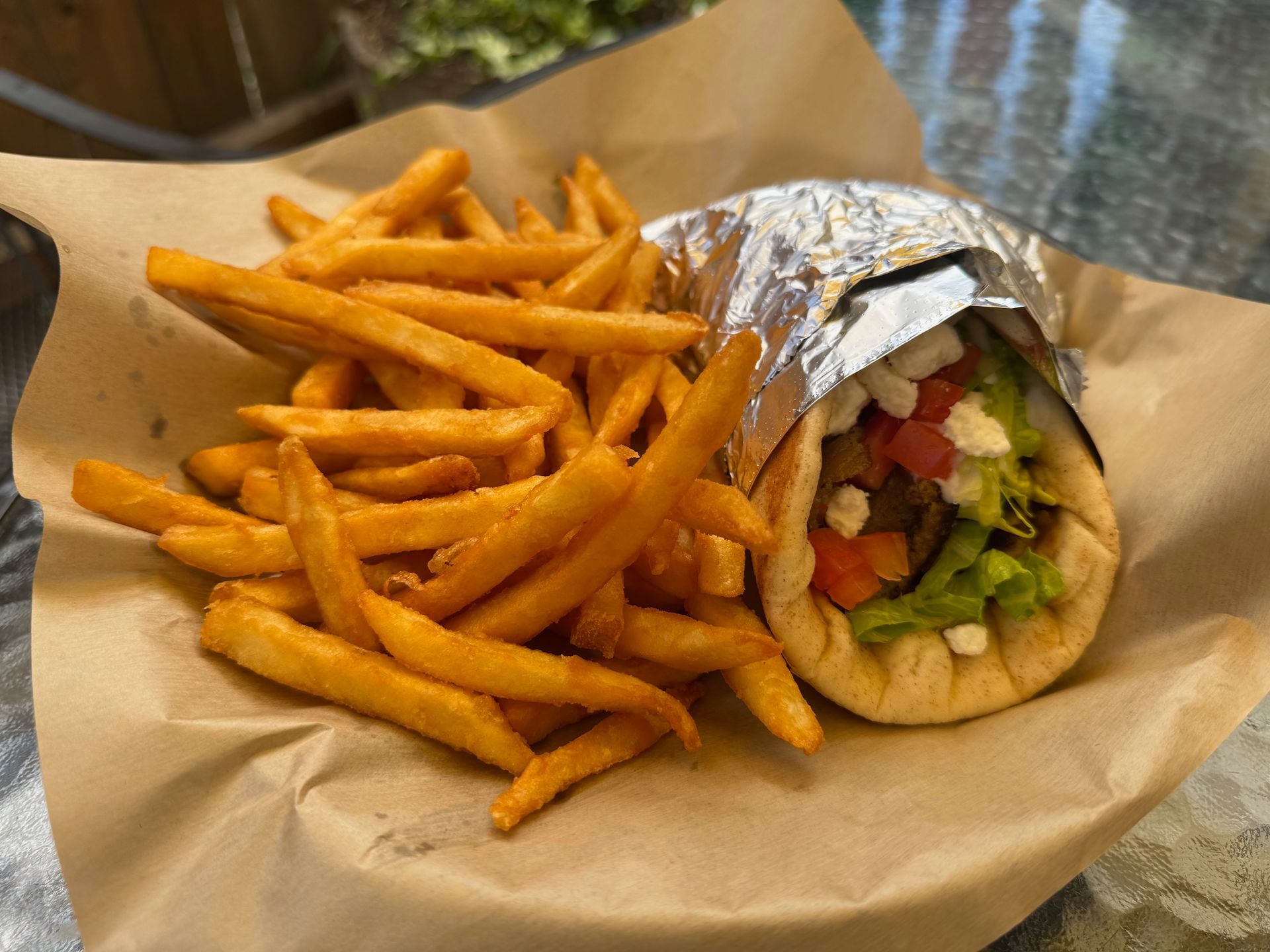 A gyro and french fries on a plate on a table.