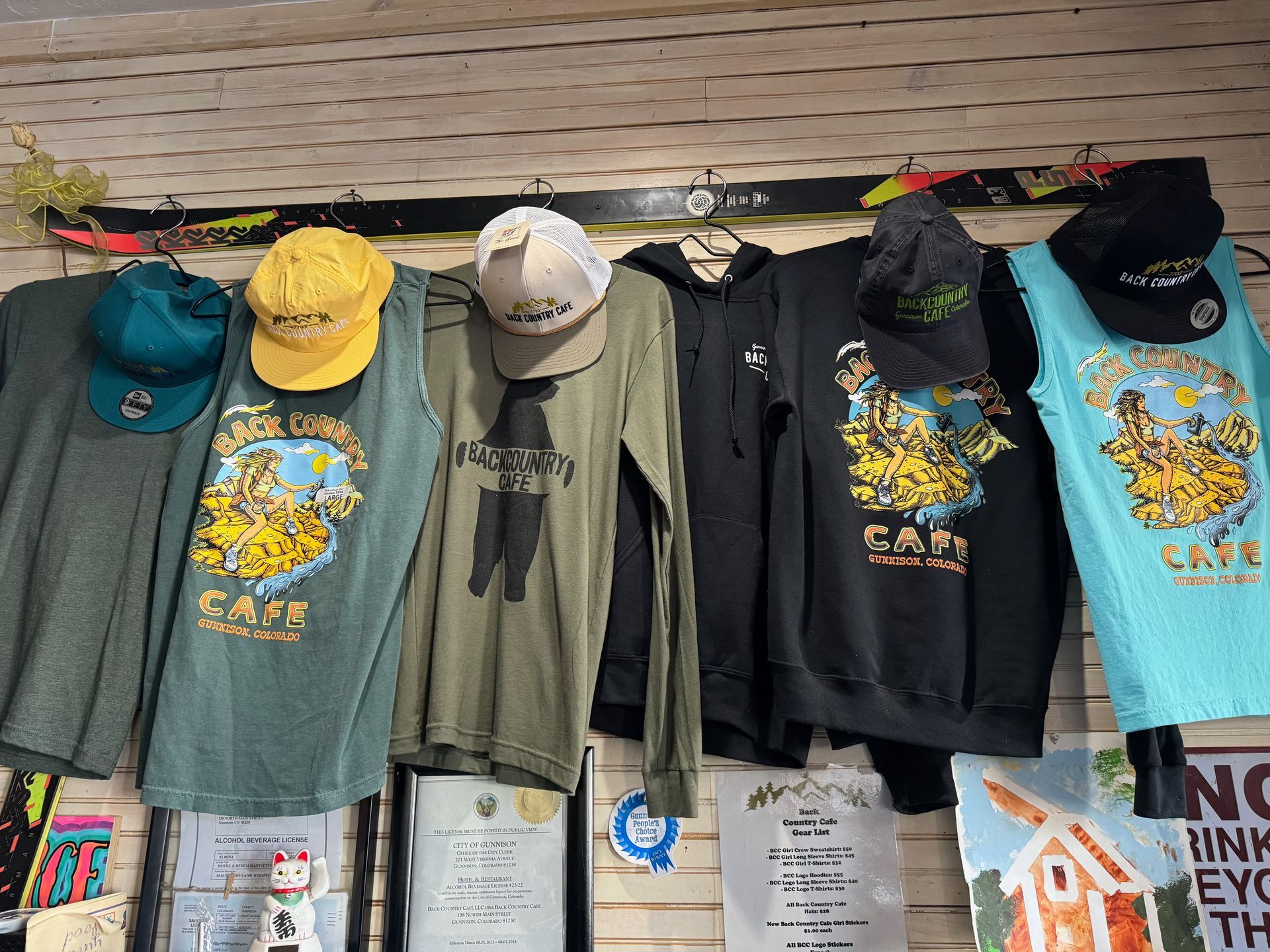 A bunch of shirts and hats hanging on a wall