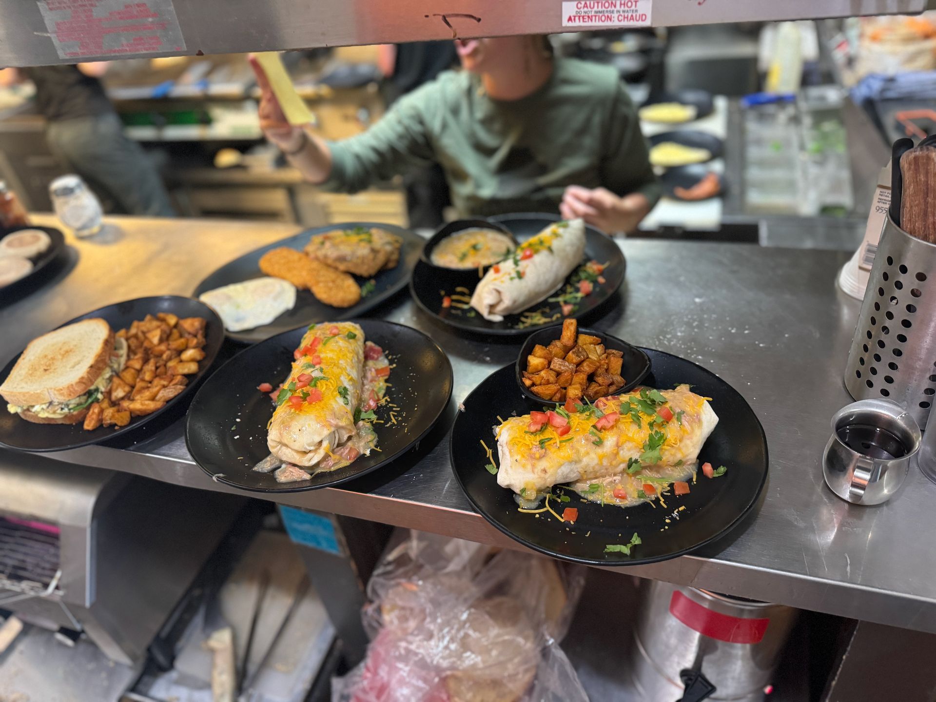 A person is standing behind a counter with plates of food on it.