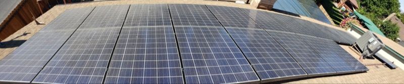 Rows of blue solar panels mounted on a rooftop, with tools and building materials nearby