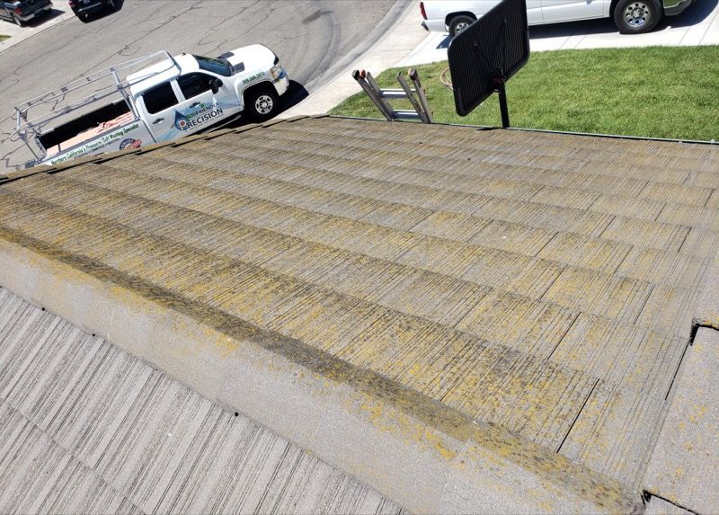 Sloped shingled roof seen from above, with a white pickup truck on the street below.