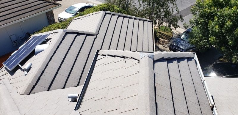 Roof damaged with missing shingles and exposed underlayment on a house roof.