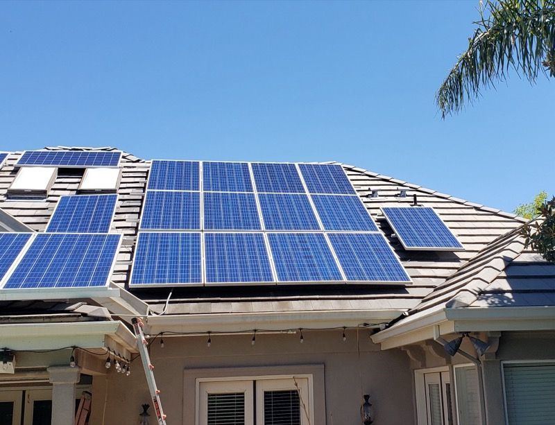 House roof covered with blue solar panels under a clear sky