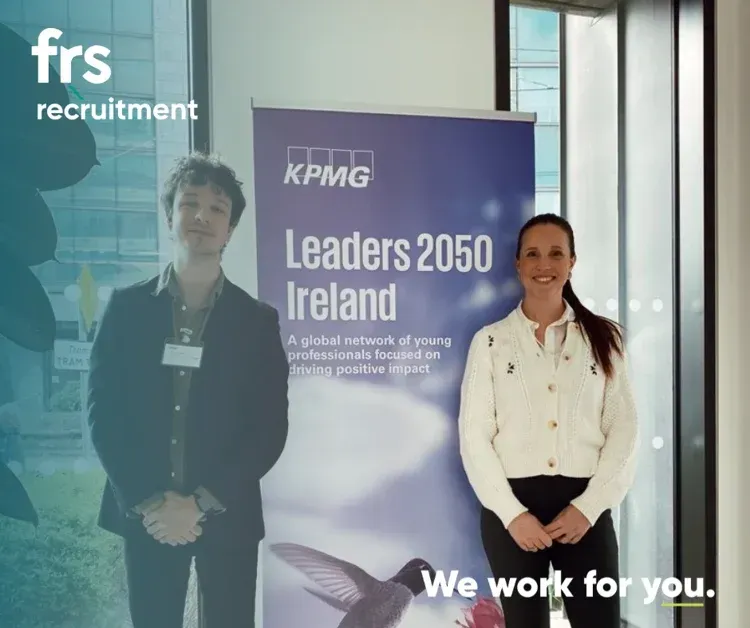 Two people stand in front of a KPMG