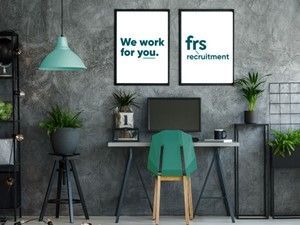 Office with desk, plants, teal chair, and framed posters: