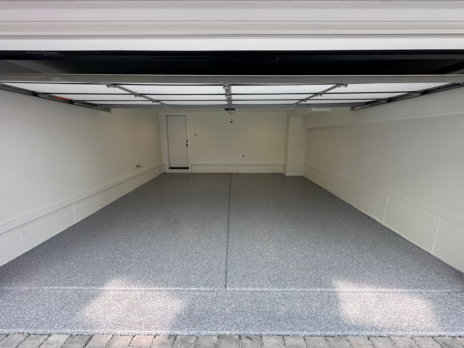 Empty garage with open door and gray speckled floor