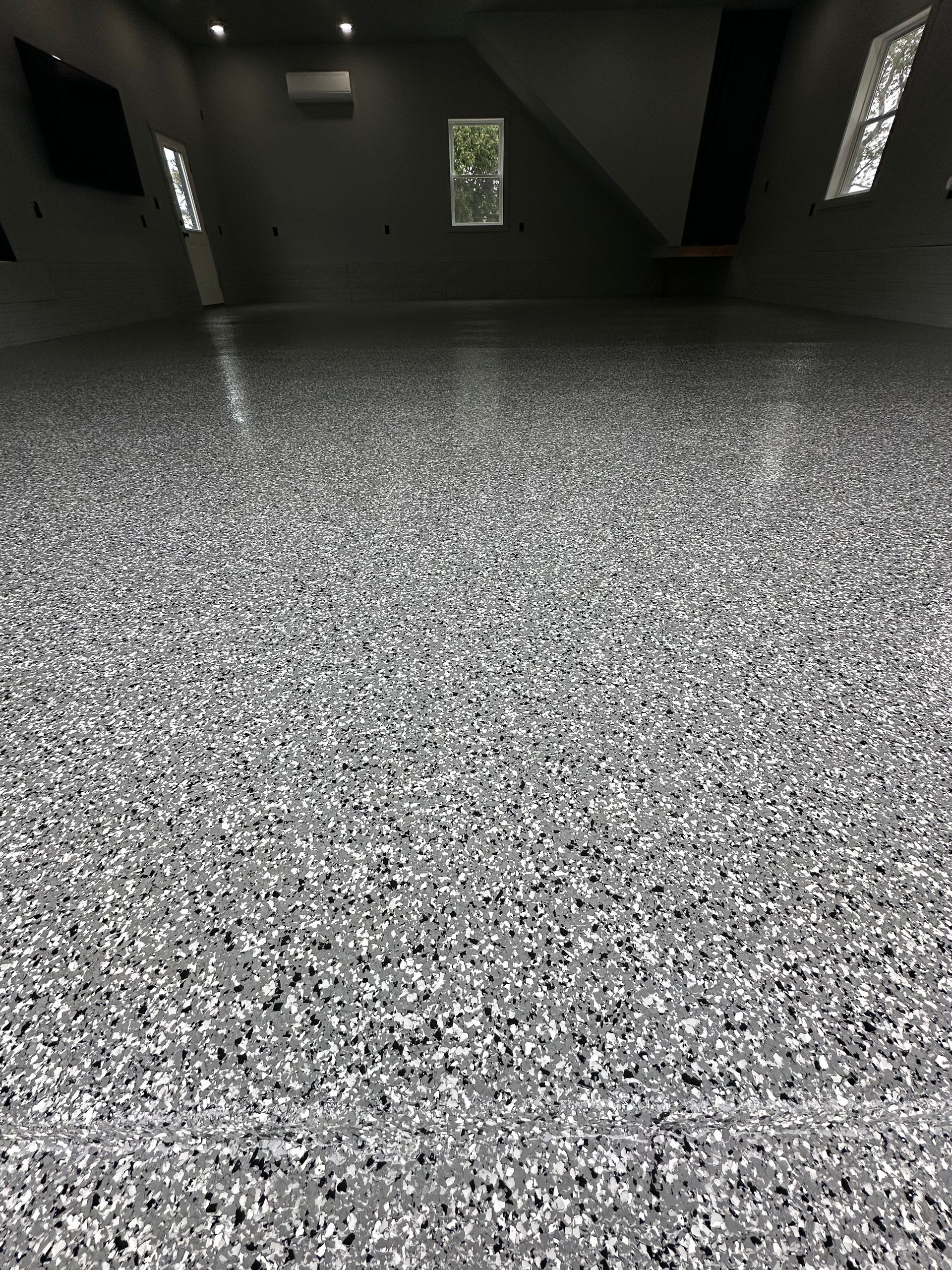 Empty dark room with speckled gray carpet and small windows.