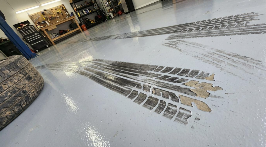 Indoor floor with tire track marks and a blurry storefront in the background
