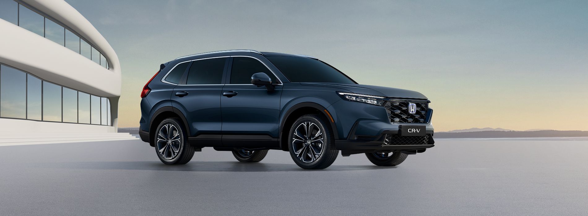 Dark blue SUV parked beside a modern building at sunset