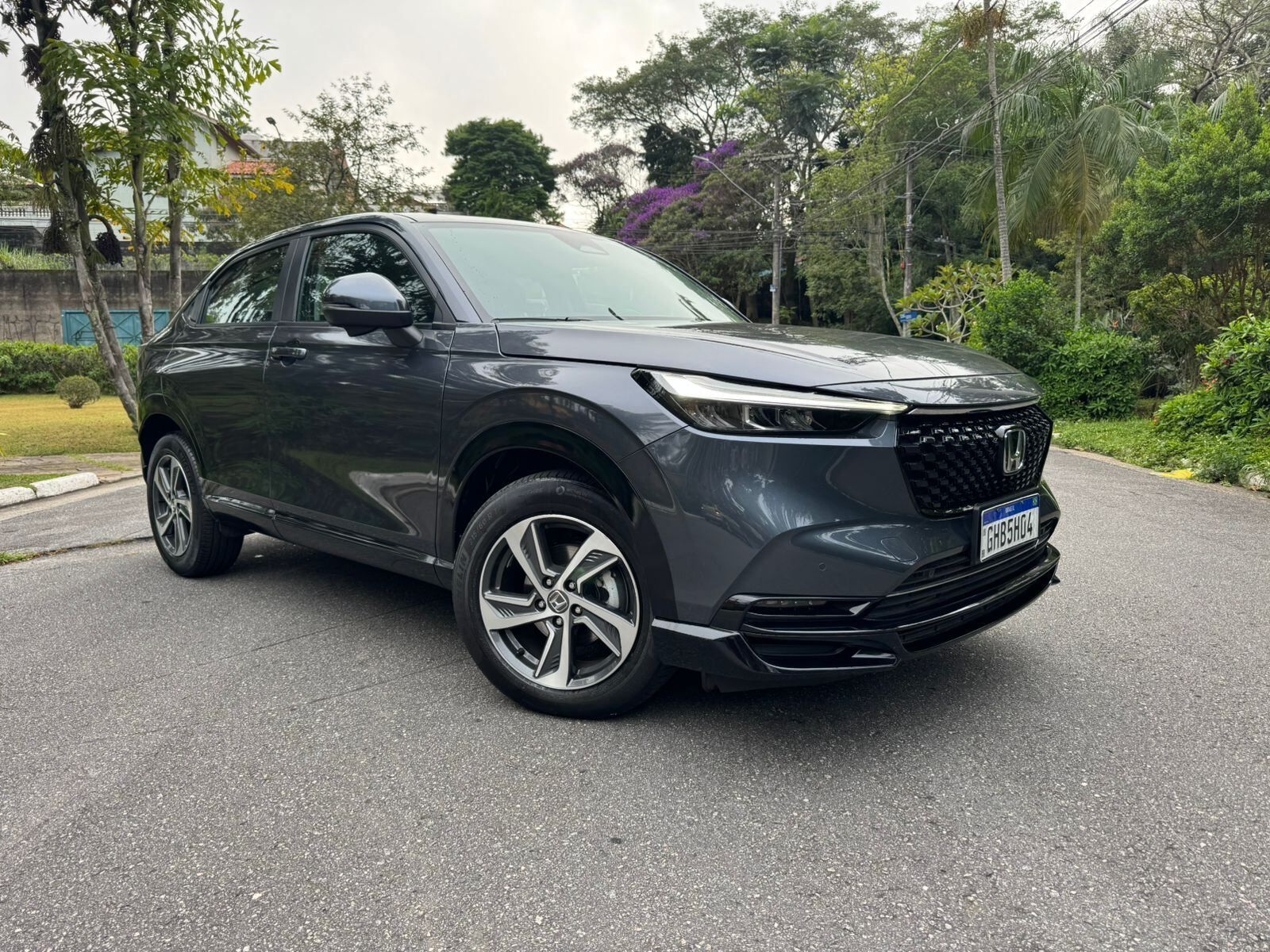 Dark gray SUV parked on a tree-lined road, front-left view
