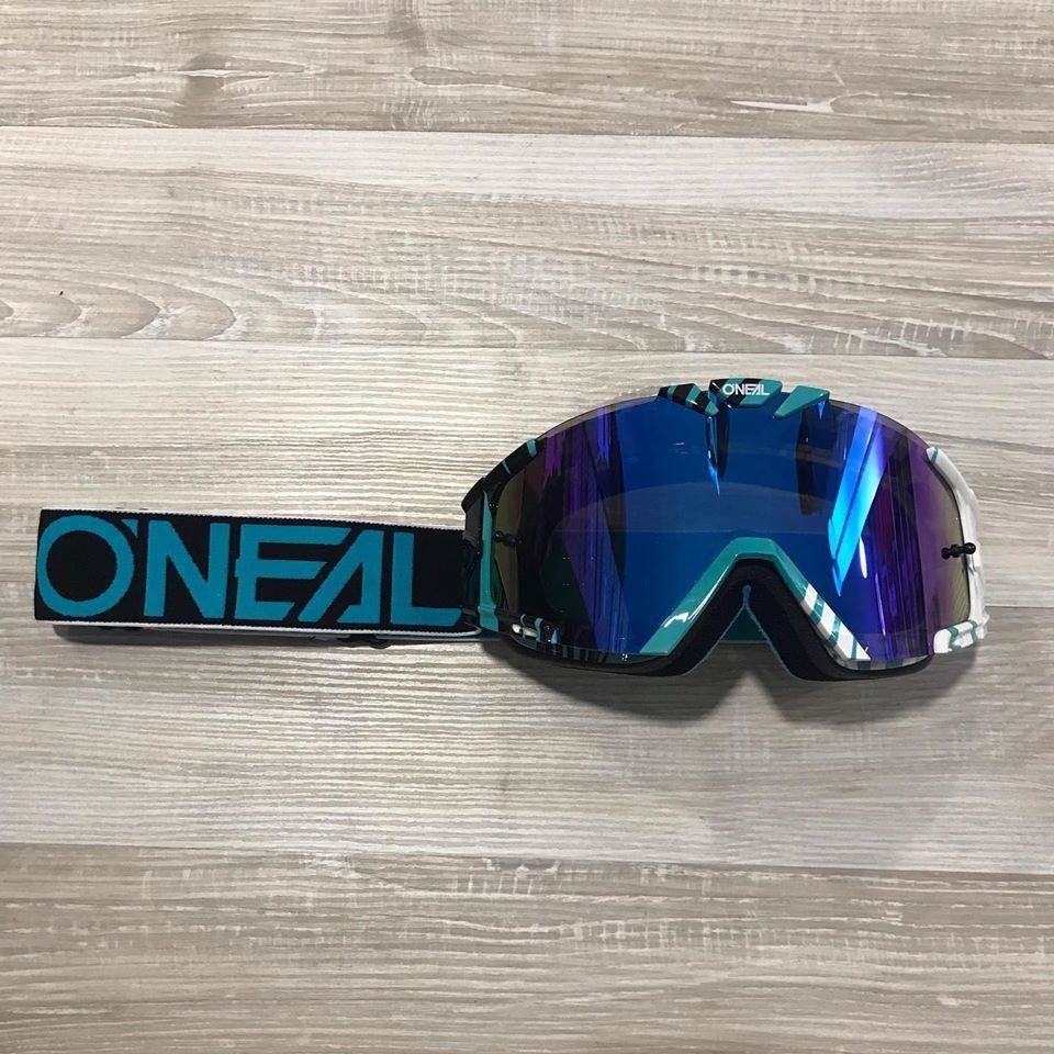 Gafas de motocross Blue O'NEAL con lente espejada sobre una superficie de madera clara.