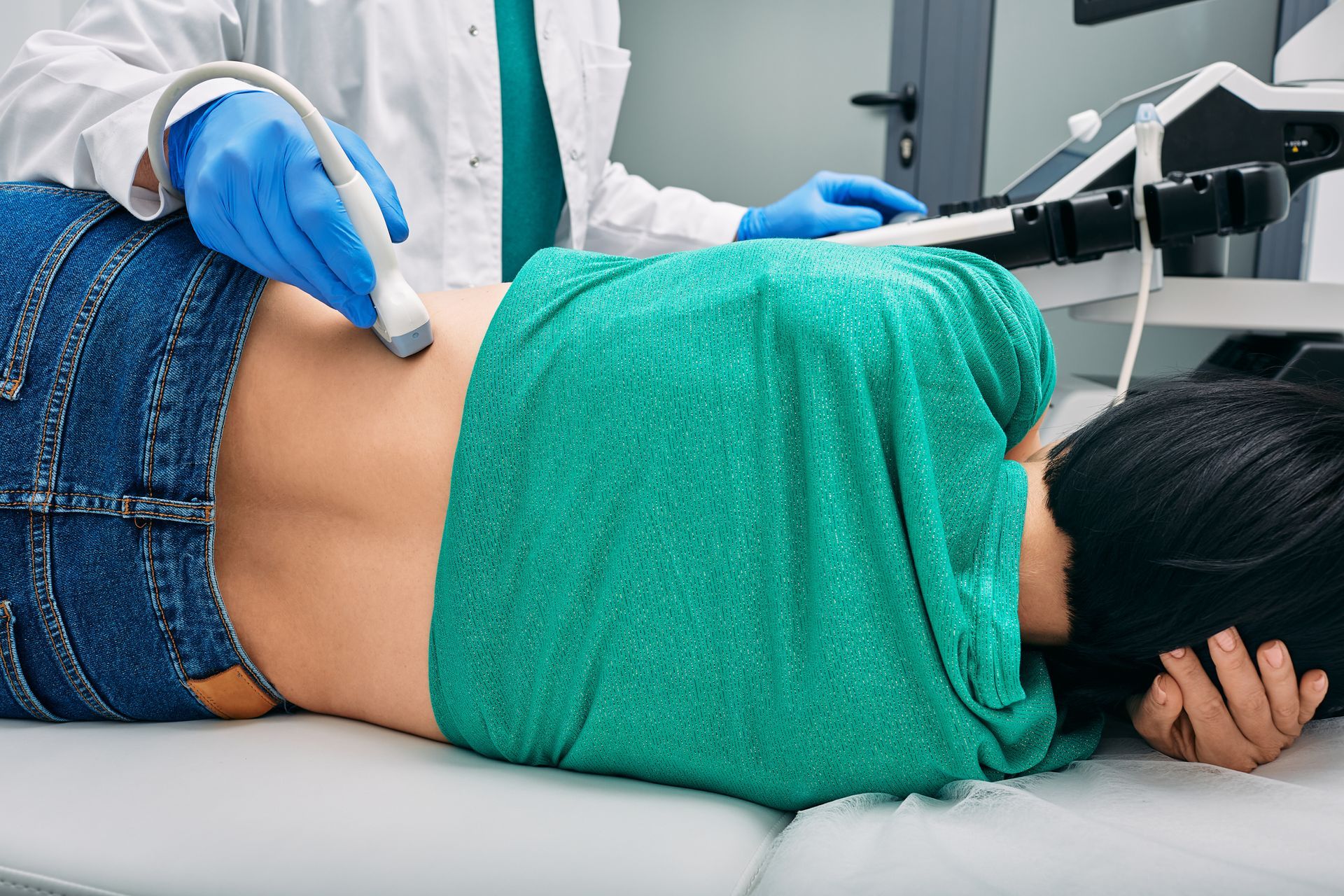Clinician using ultrasound probe on patient's lower abdomen during exam