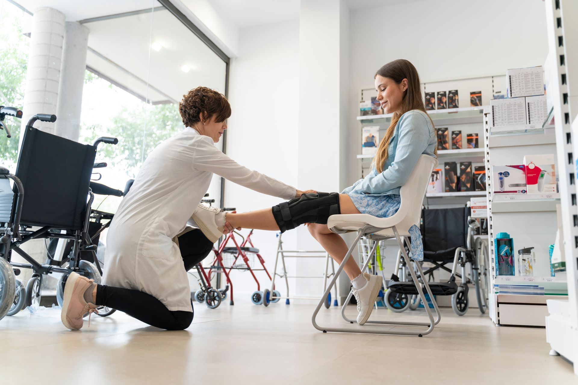 An orthopedist adjusting a seated client’s leg in a bright rehabilitation clinic