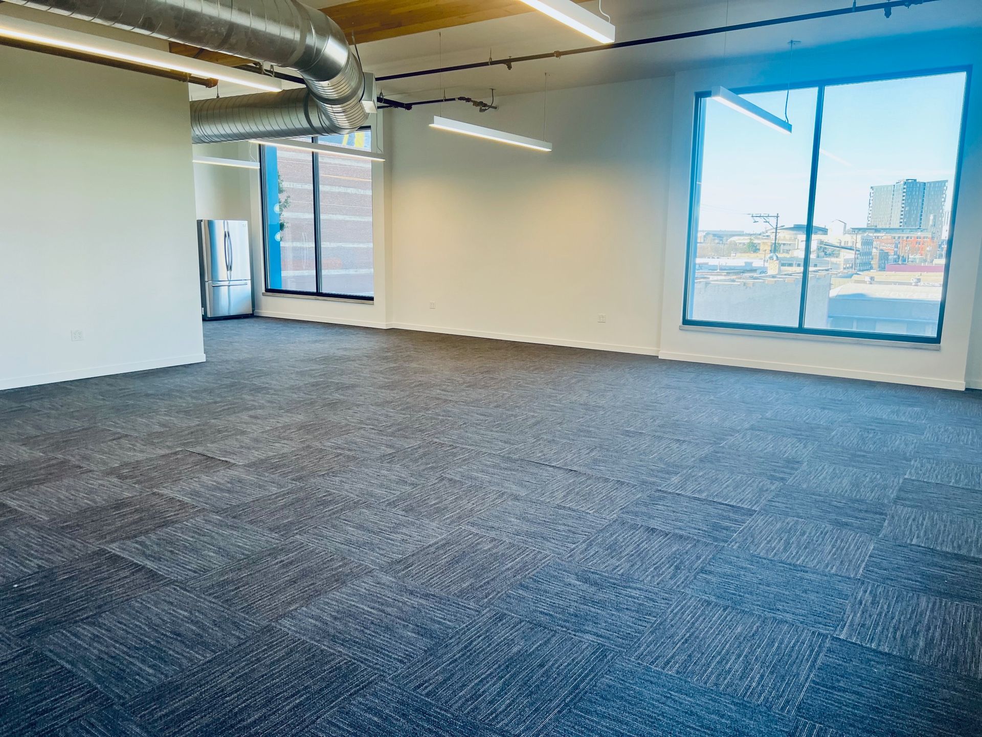 A large empty room with a carpeted floor and a lot of windows.