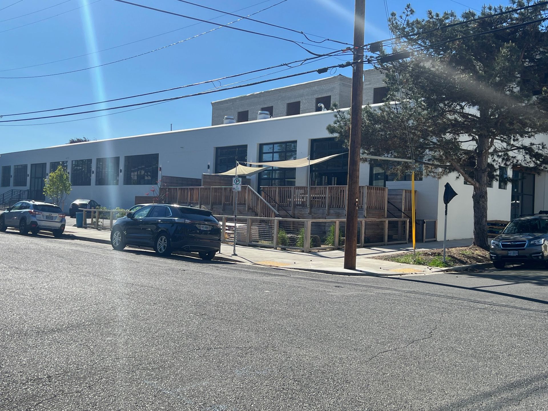 A row of cars are parked on the side of the road in front of a building.