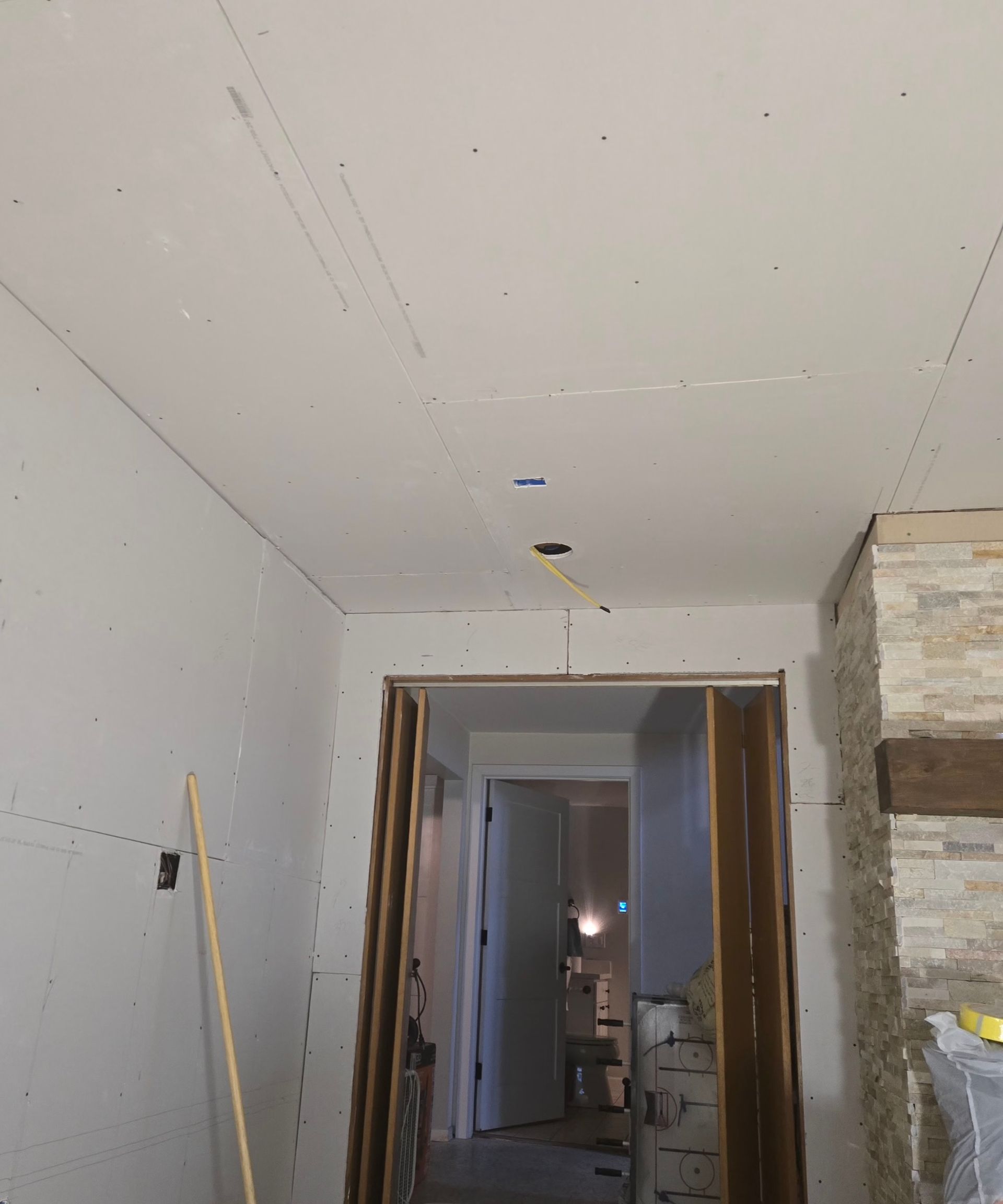 An unfinished doorway and ceiling featuring installed drywall panels, seams, and exposed electrical box cutouts.
