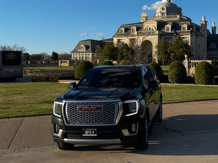 Black SUV parked on a driveway in front of an ornate stone mansion on a sunny day onxy black car service dallas fort worth texas