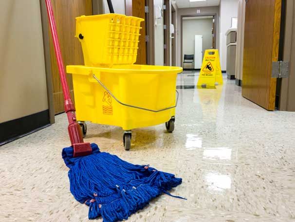 Blue mop and yellow bucket on wheels, wet floor caution sign, hallway.