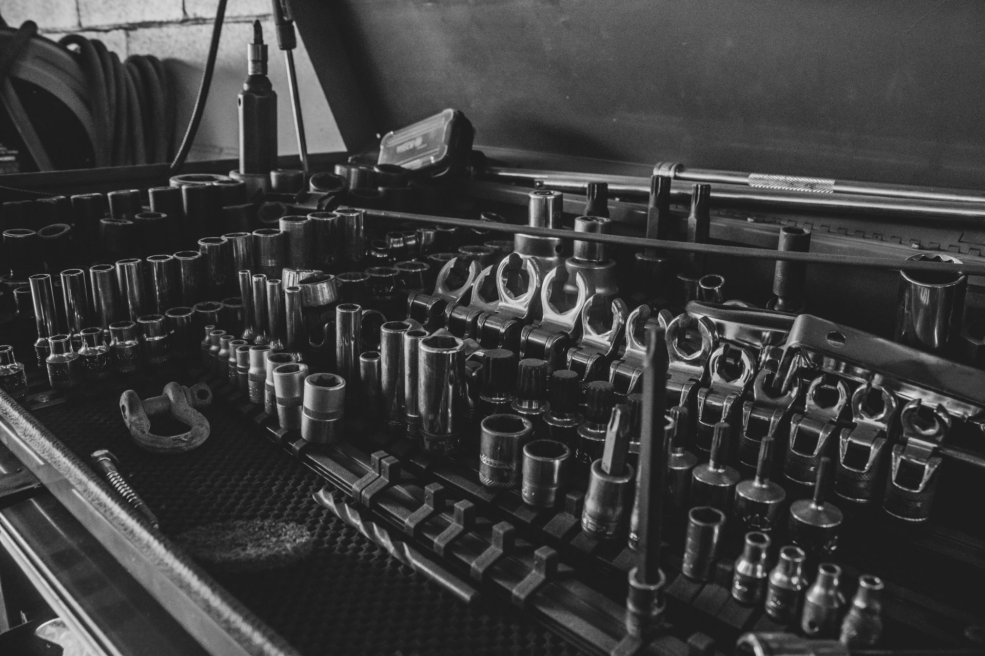 Black and white photo of a workbench with organized sockets and tools.