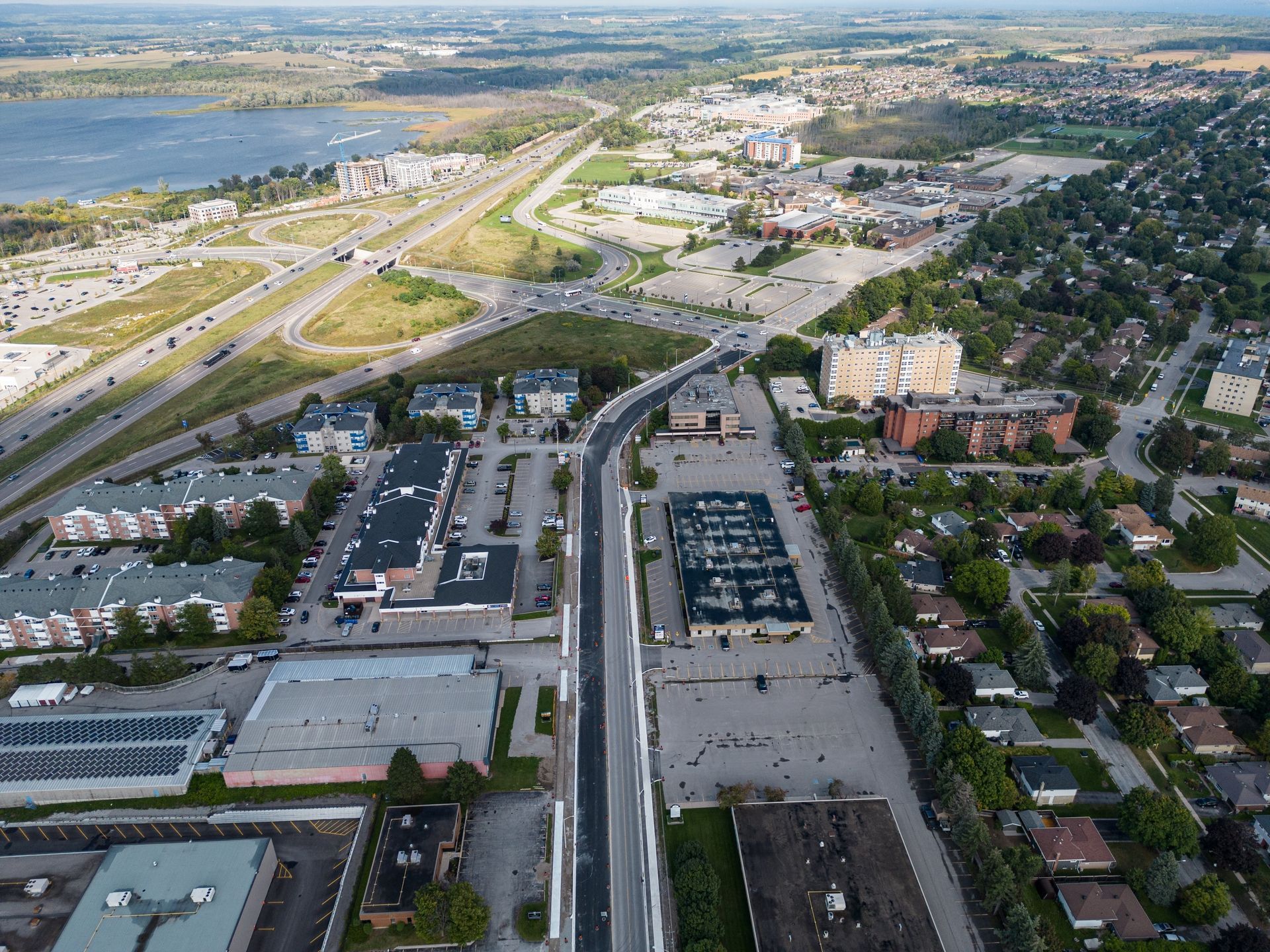 Aerial view of city with roads, buildings, and a body of water in the distance.