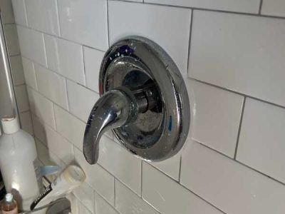 Chrome shower valve on white subway tile.