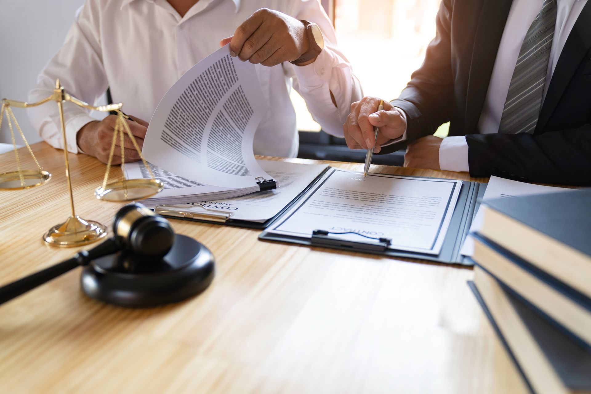 Two men at a desk tearing up a document; gavel and scales of justice present.