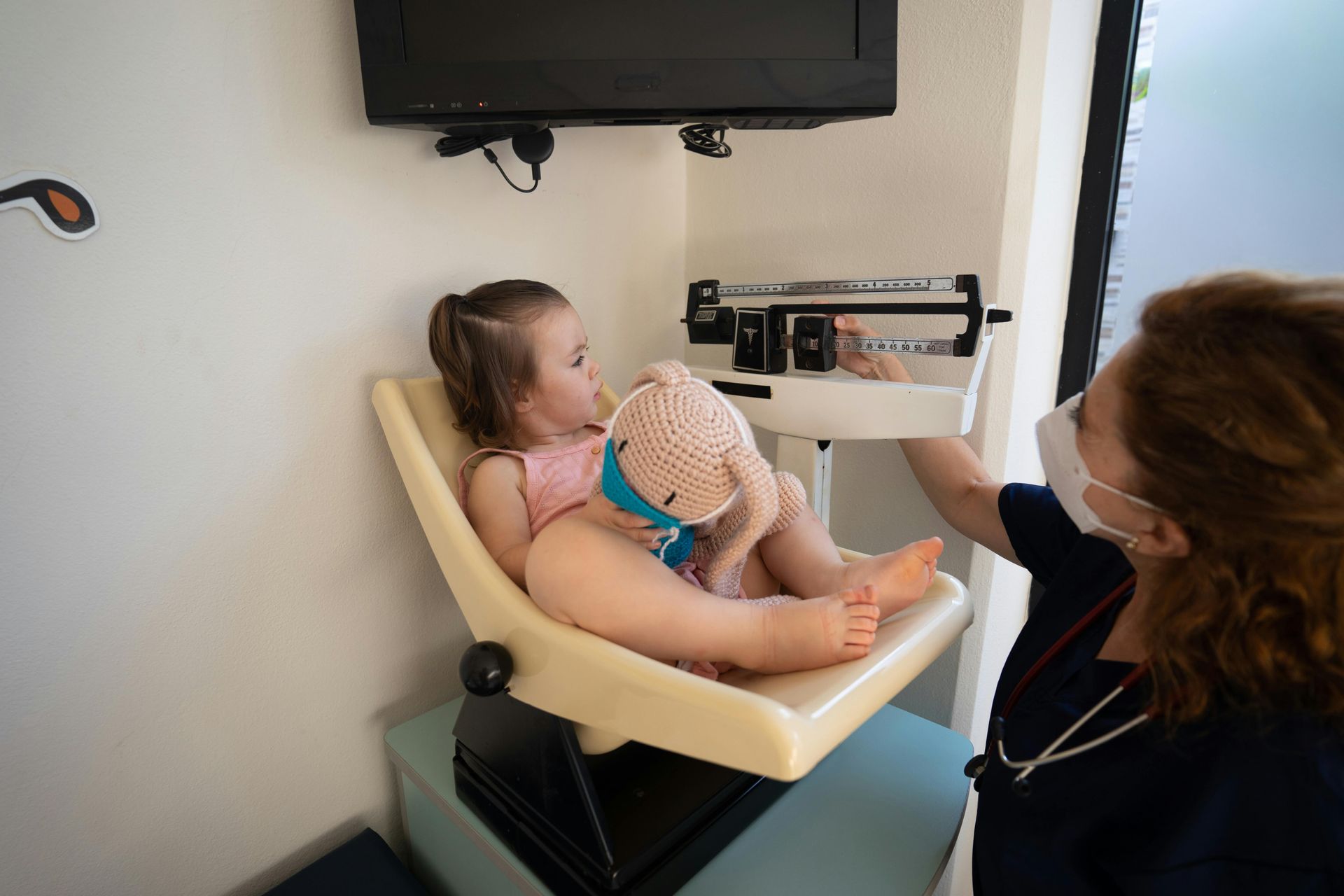 Toddler being weighed by a pediatric nurse at a wellness visit.