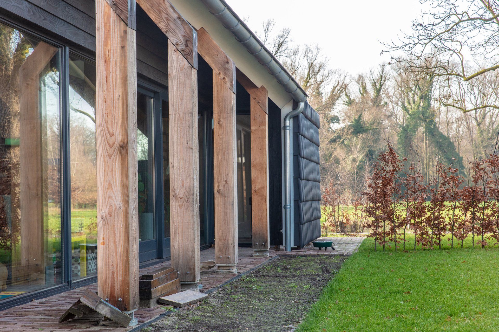 Er wordt een huis gebouwd met veel ramen en houten balken.