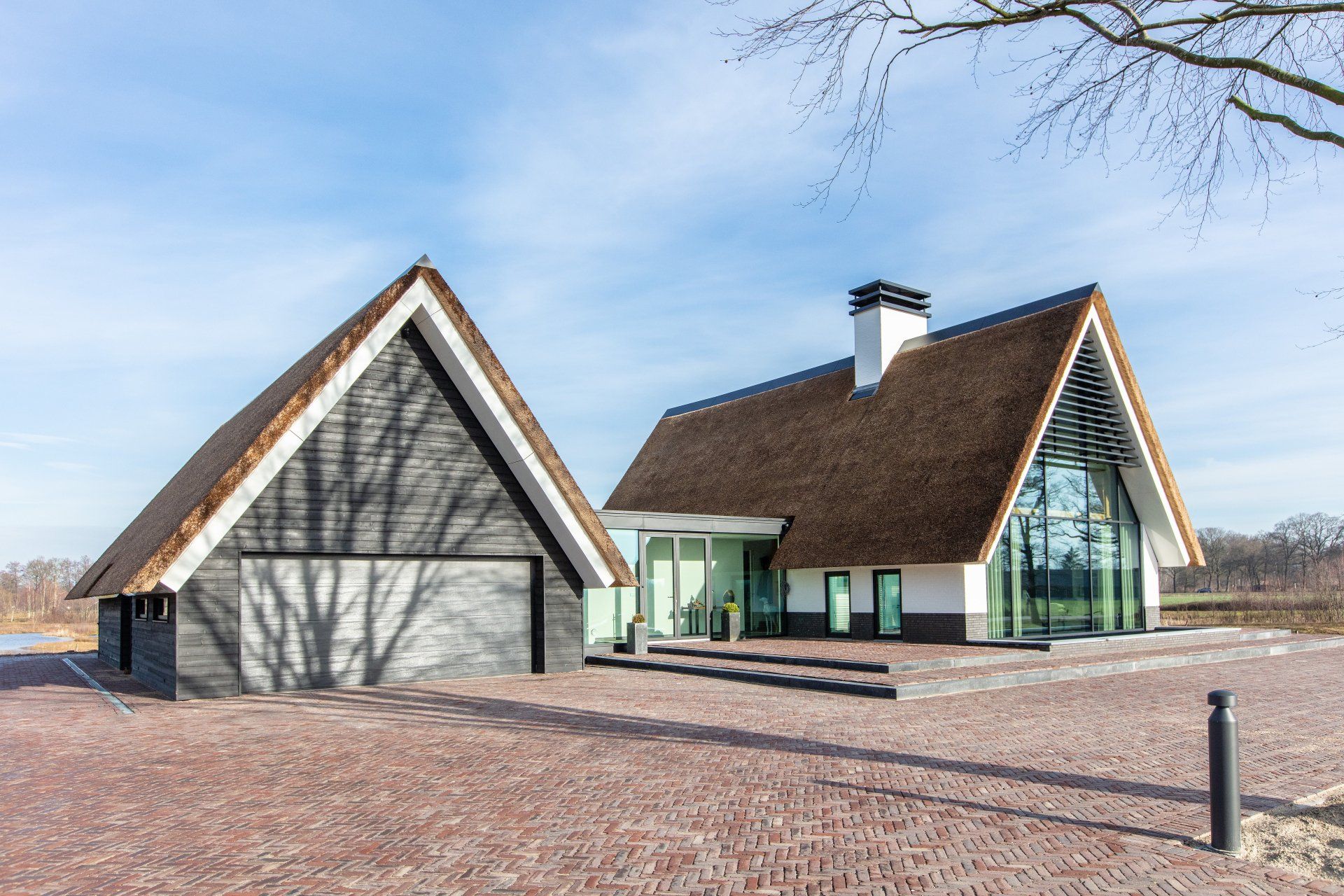 Een wit huis met een rieten dak en een garage.