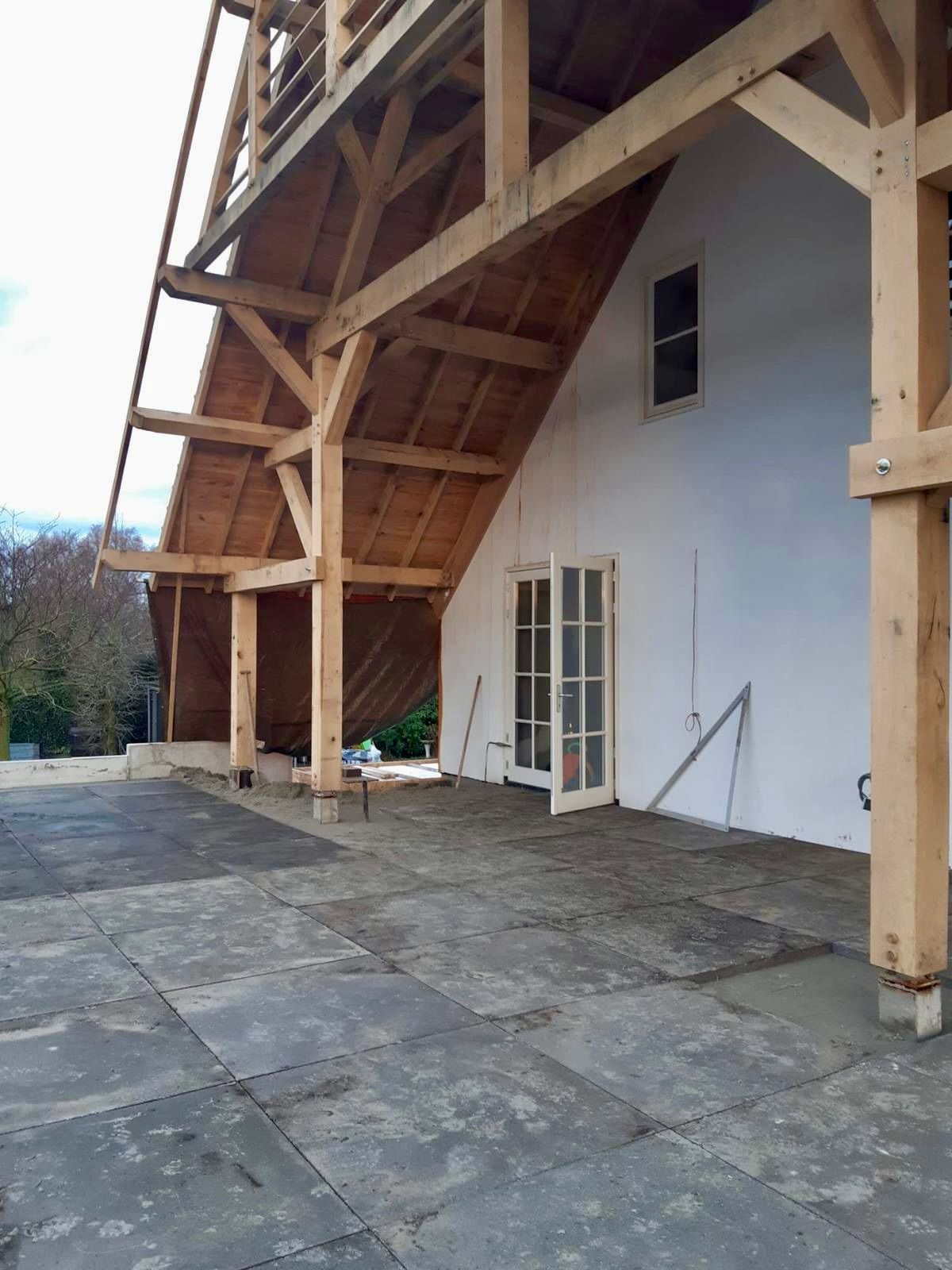 Een groot wit gebouw met een houten dak en een patio ervoor.