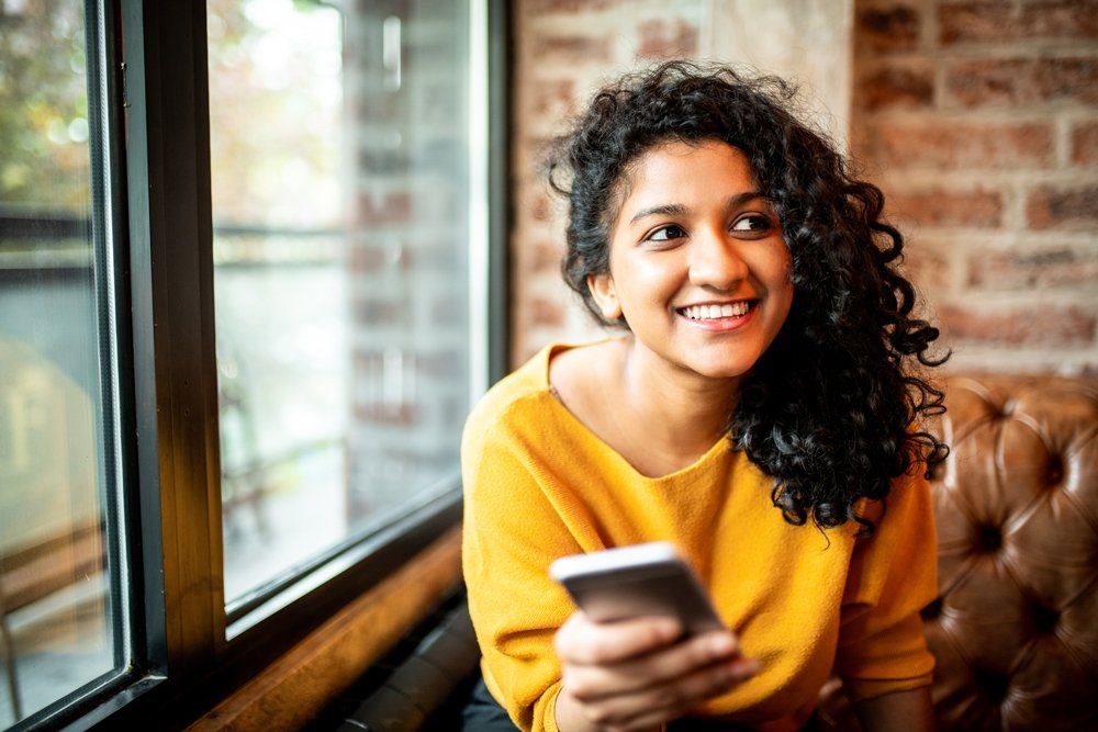 Smiling Woman Using Her Phone — Riverdale, GA — Tara Gynecology Smiling Woman Using Her Phone — Riverdale, GA — Tara Gynecology