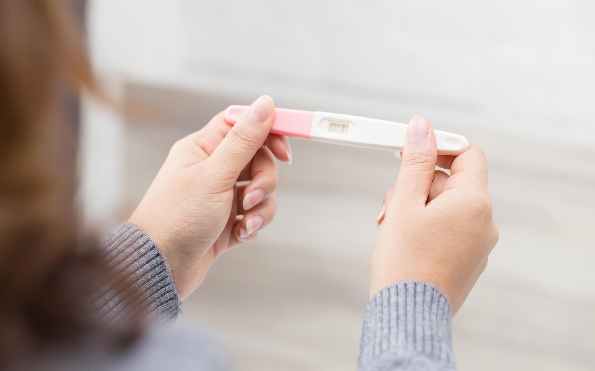 Person holding a home pregnancy test while viewing the result. Person holding a home pregnancy test while viewing the result.