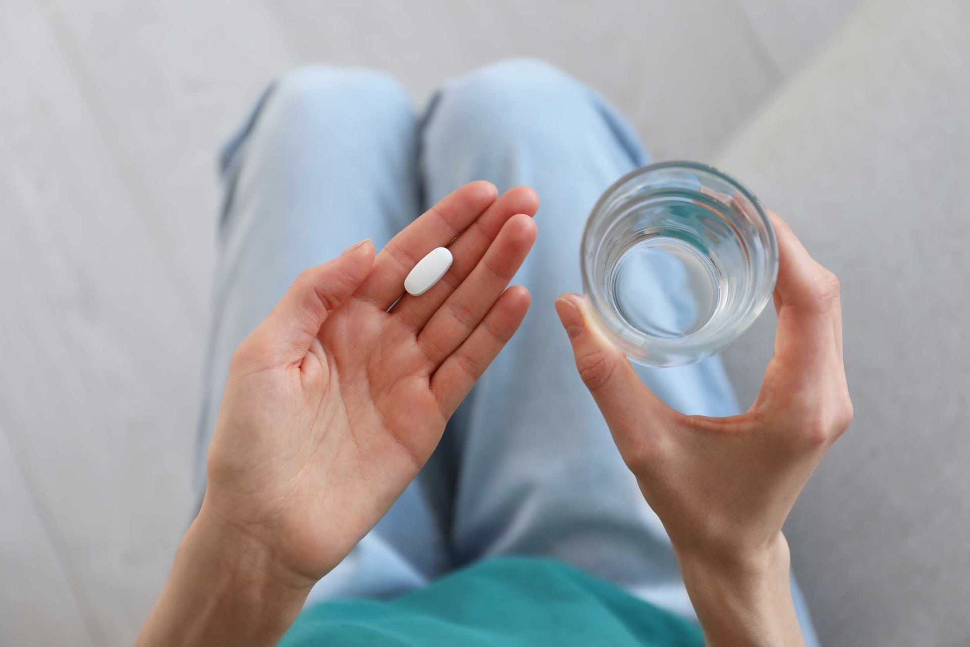 Top view of a young woman with an abortion pill and a glass of water, showcasing abortion services. Top view of a young woman with an abortion pill and a glass of water, showcasing abortion services.