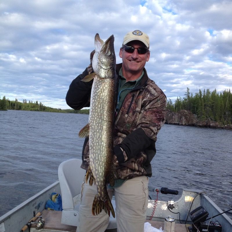 A man in a boat is holding a large fish as an experienced lake home owner