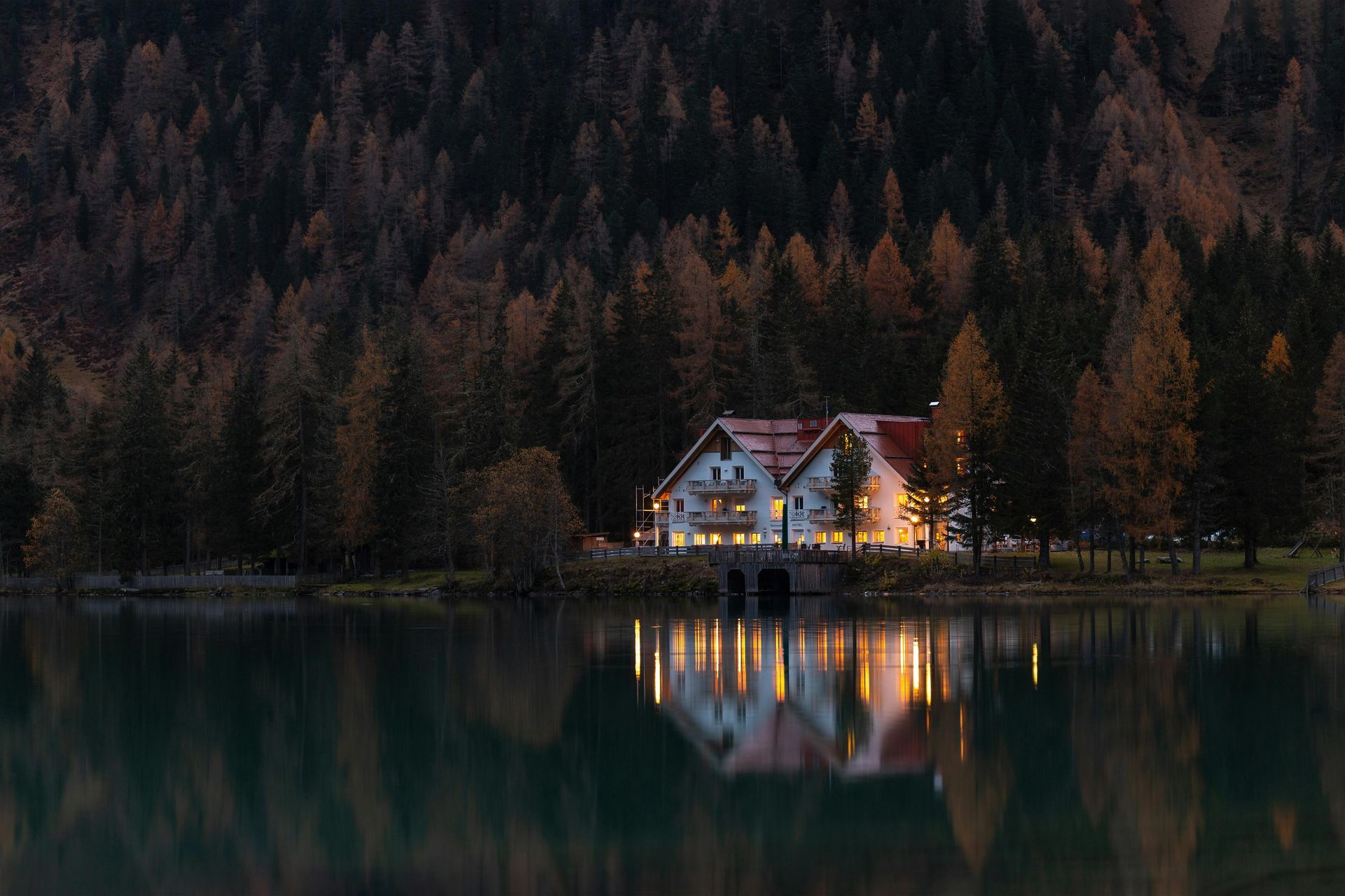 A house is sitting on the shore of a lake in the middle of a forest.