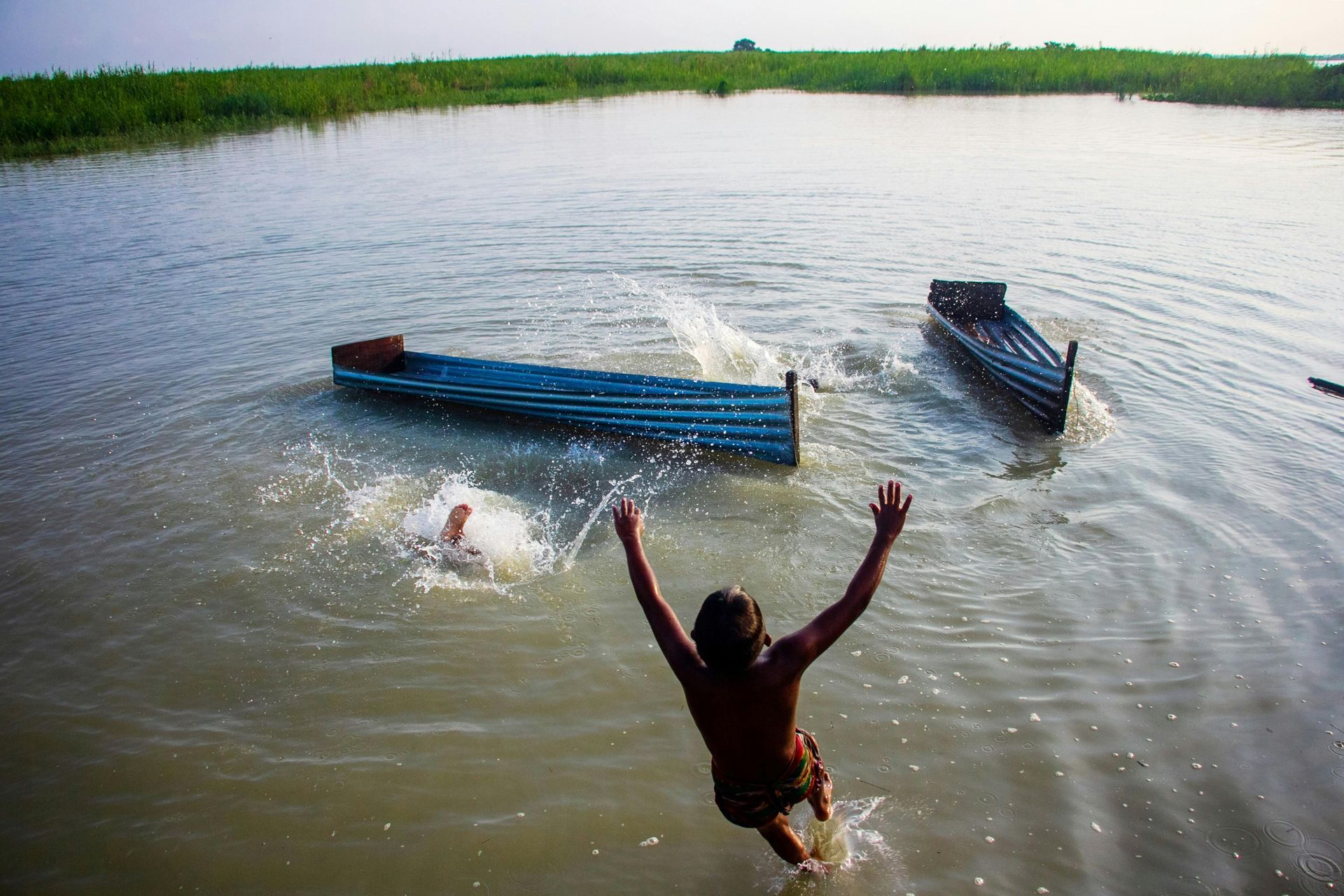 A man is jumping into a body of water with his arms outstretched.