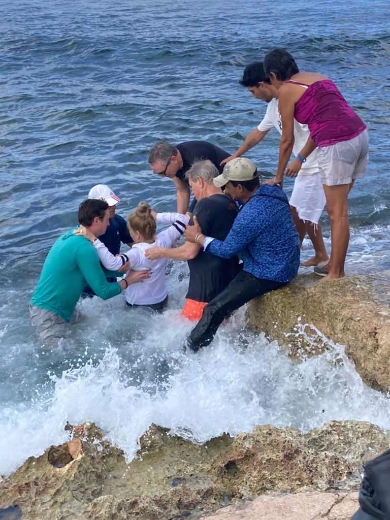 A group of people are sitting on rocks near the ocean.