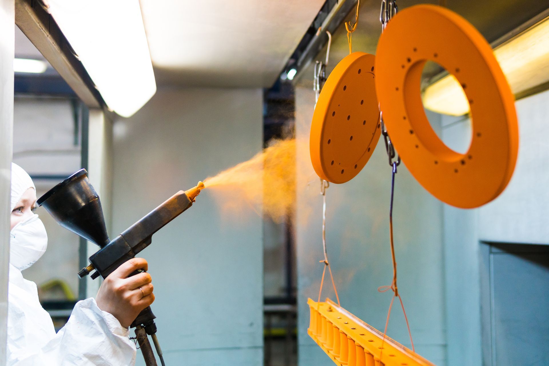Une personne pulvérise de la peinture orange sur un morceau de métal.