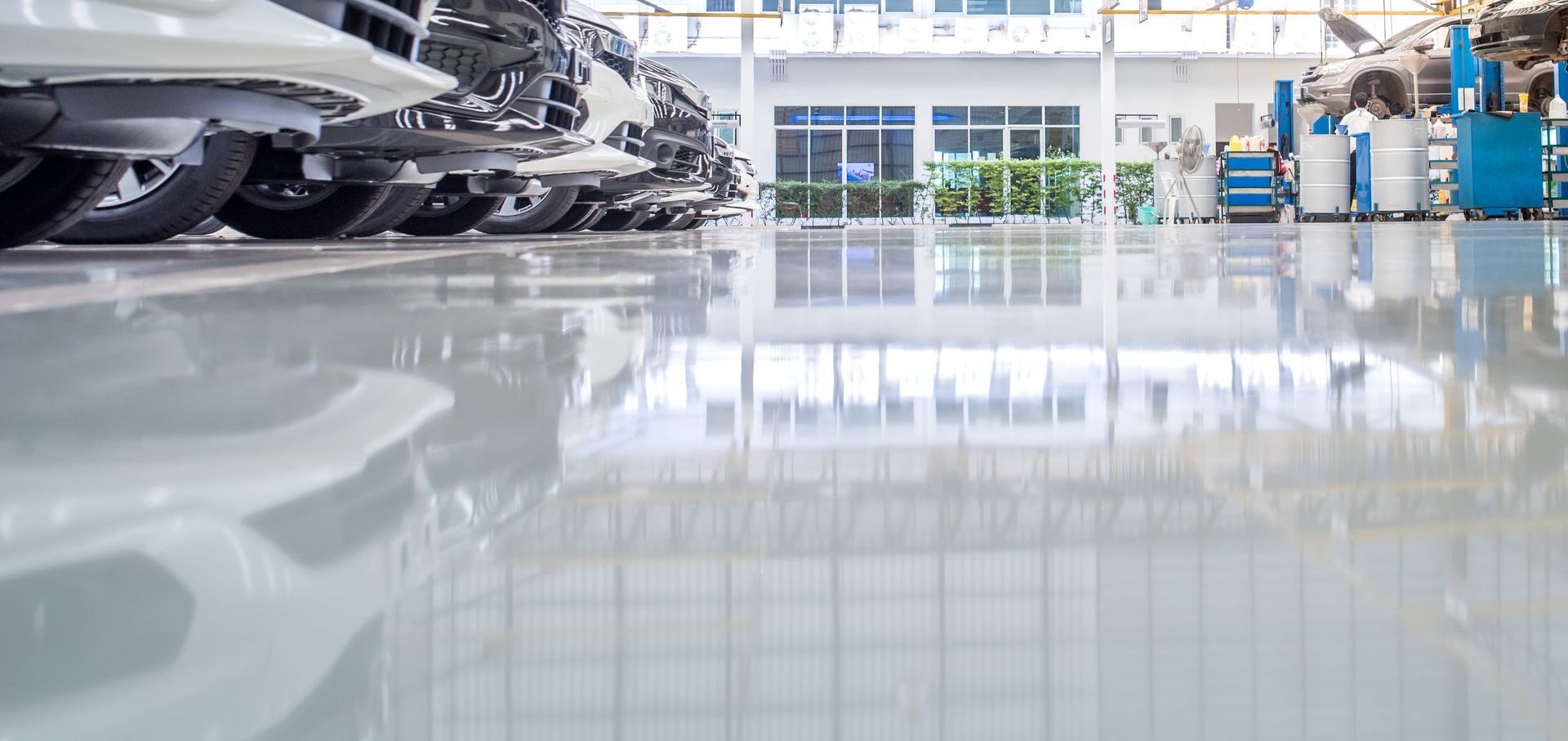 Le sol brillant reflète les voitures garées dans un garage moderne.